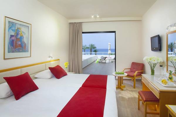 Ein Hotelzimmer im Queens Bay mit Meerblick, einem Doppelbett, einem Schreibtisch und einem Balkon.
