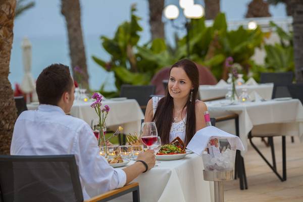 Ein Paar isst im Hotelrestaurant Queens Bay mit Blick auf das Meer.