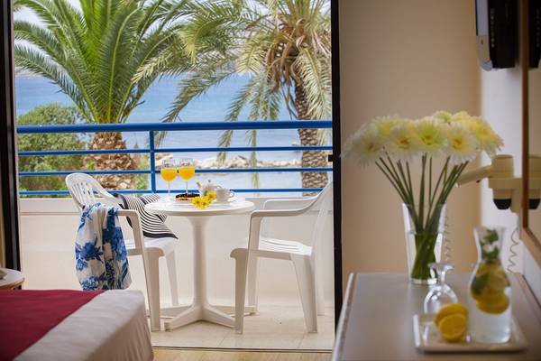 Terrasse des Queens Bay Hotels mit Blick auf das Meer und Palmenbäume.