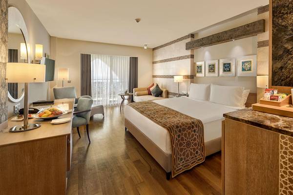 Innenansicht eines Hotelzimmers im Kempinski Hotel The Dome Belek mit Bett, Schreibtisch und Aussichtsfenster.