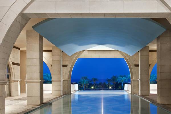 Nachtansicht des Swimmingpools im Kempinski Hotel The Dome Belek mit Blick auf die Palmen und den Horizont