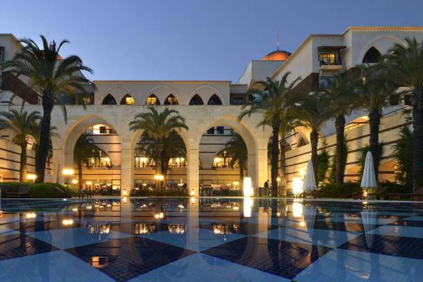 Außenansicht des Kempinski Hotel The Dome Belek mit Pool und Palmen