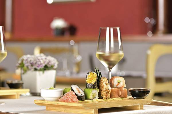 Ein Tisch mit Sushi-Platten, Wein und Weinglas in einem Restaurant.