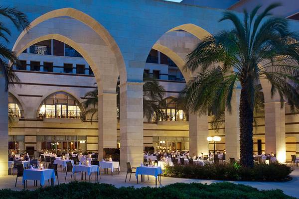 Außenbereich des Kempinski Hotel The Dome Belek mit gebogenen Säulen und Palmen.