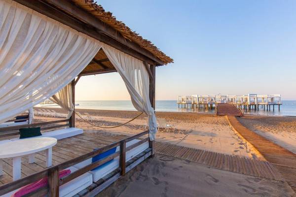 Kempinski Hotel The Dome Belek Strand mit weißen Vorhängen und Tischen.