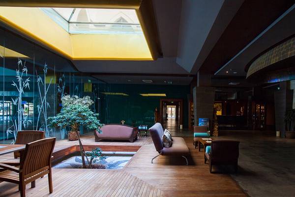 Lobby des Kempinski Hotel The Dome Belek mit Holzboden, Sitzbereichen und Pflanzen.