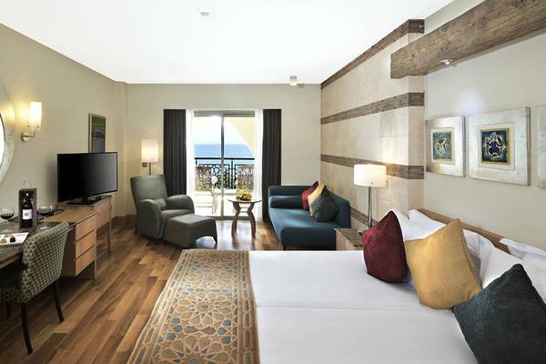 Luxuriöses Zimmer im Kempinski Hotel The Dome Belek mit Doppelbett, Schreibtisch, Fernseher und Balkon.