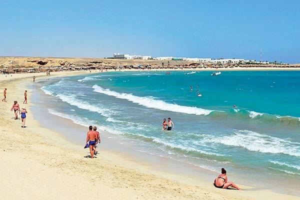 Besucher genießen den Strand am Malikia Resort Abu Dabbab mit kristallklarem Wasser und blauem Himmel.