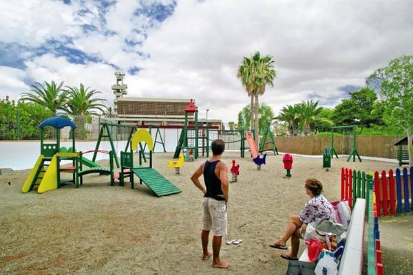 Spielplatz im Alborada Ocean Club Hotel mit bunten Spielgeräten und einem Erwachsenen, der darauf blickt.