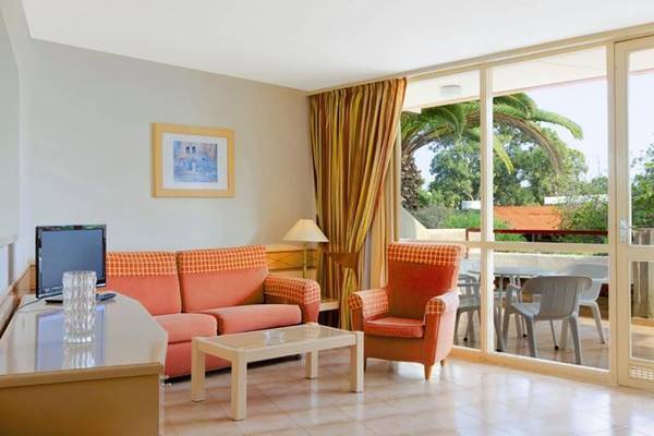 Wohnzimmer im Alborada Ocean Club Hotel mit Sofa, Sessel, Tisch und Fernseher.