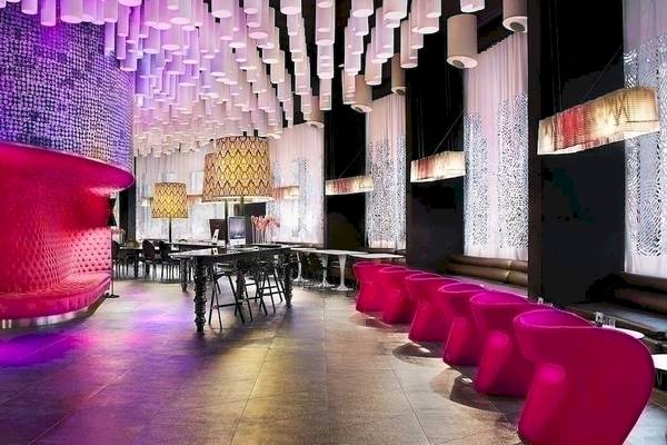 Das Interieur des Barcelo Raval Hotels mit violetten Wänden, roten Stühlen und einer langen Tischreihe.