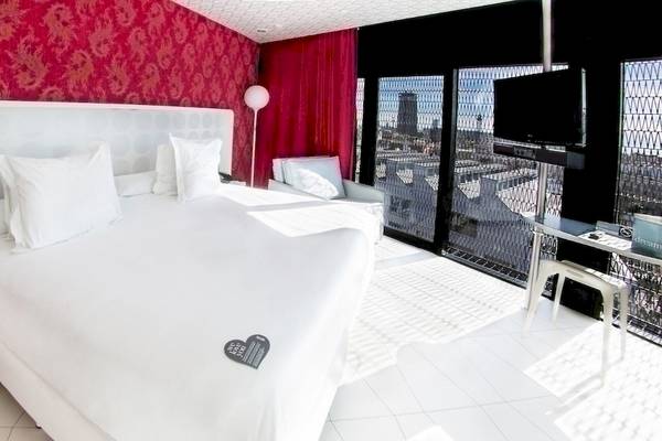 Hotelzimmer im Barcelo Raval mit weißem Bett, roter Wand und Fernseher auf dem Schreibtisch