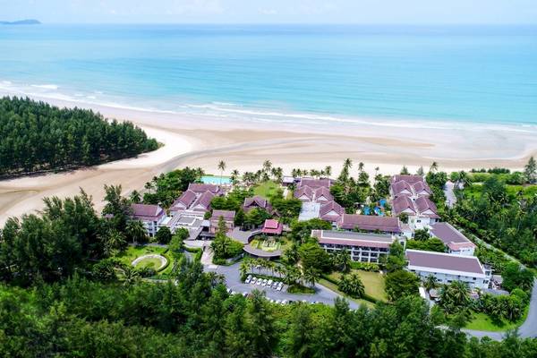 Luftaufnahme des Apsara Beachfront Resorts und Villas an einer Küste mit blauem Meer und weißem Sandstrand.