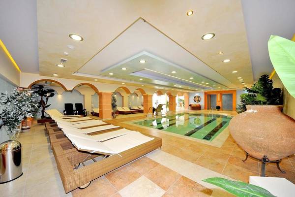 Innenpool des Gaia Palace Hotels mit Liegen und Pflanzen.
