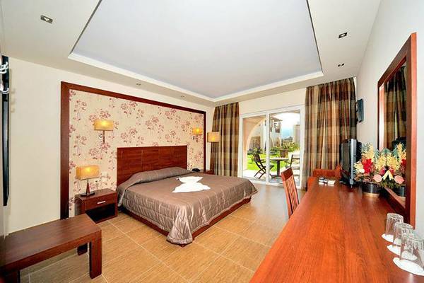 Schlafzimmer im Gaia Palace Hotel mit Bett, Tisch, Stuhl und Fenster mit Gartenblick.