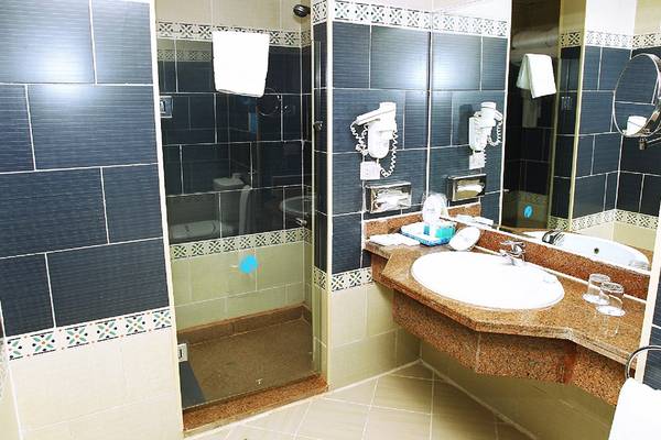 Badezimmer des Sentido Mamlouk Palace Hotels mit blauen Fliesen, Duschkabine und Waschbecken.