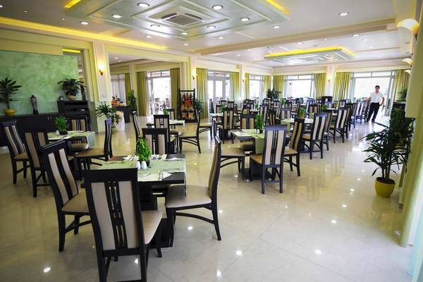 Restaurantsaal im Gaia Palace Hotel mit gedeckten Tischen und grünen Pflanzen.
