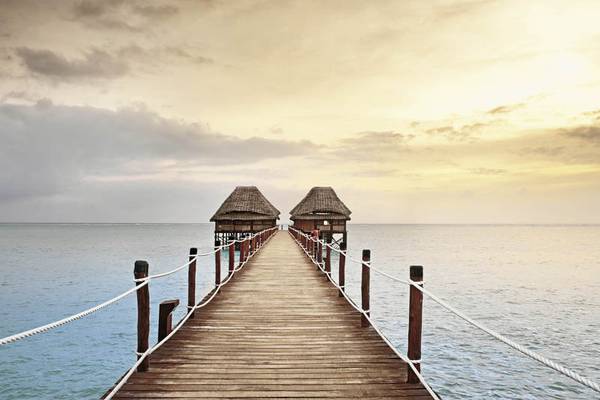 Langer Steg zum Melia Zanzibar Hotel am Meer mit zwei Hütten.