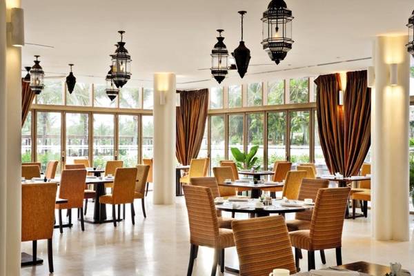 Innenansicht des Restaurants im Melia Zanzibar Hotel mit runden Tischen und Stühlen.