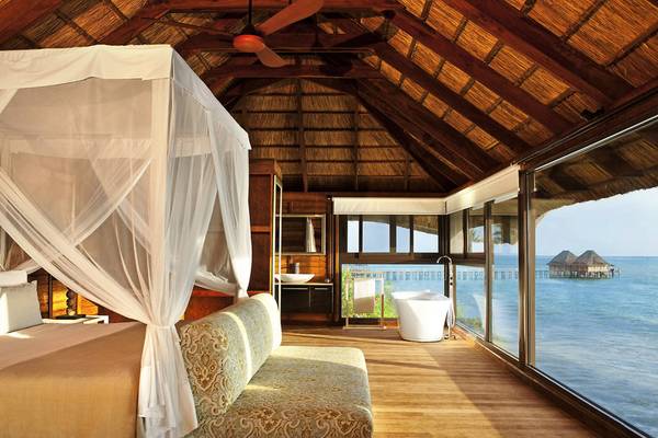 Luxuriöse Suite im Melia Zanzibar mit Meerblick, Bett mit Baldachin, Badewanne und großen Fenstern.