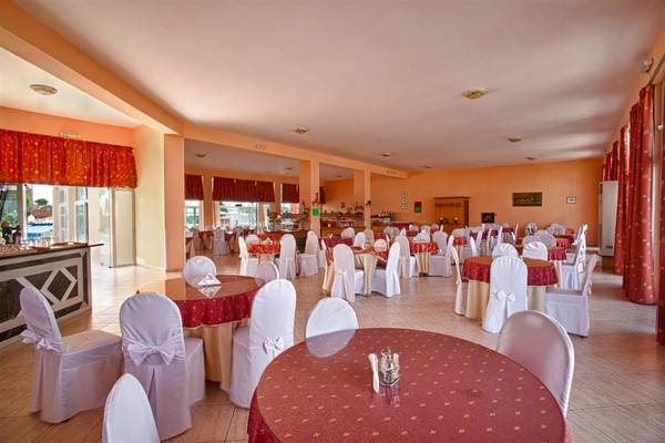 Restaurant im Ilios K. Village Resort mit roten und weißen Tischdecken und Stühlen.