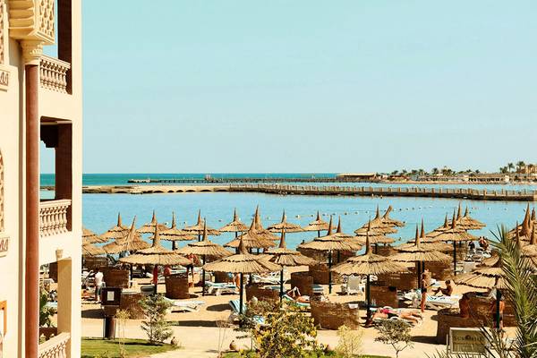 Strandansicht des Sentido Mamlouk Palace Hotels mit vielen Sonnenschirmen und Gästen.