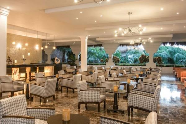 Die Lobby des Grand Riviera Princess Hotels mit Bar, Stühlen und Tischen.
