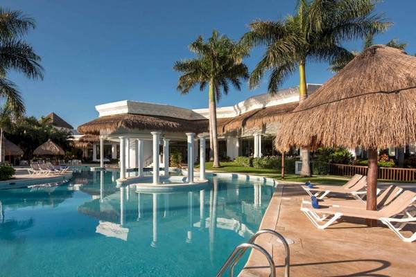 Außenpool des Grand Riviera Princess Hotels mit weißen Sonnenliegen und Palmen