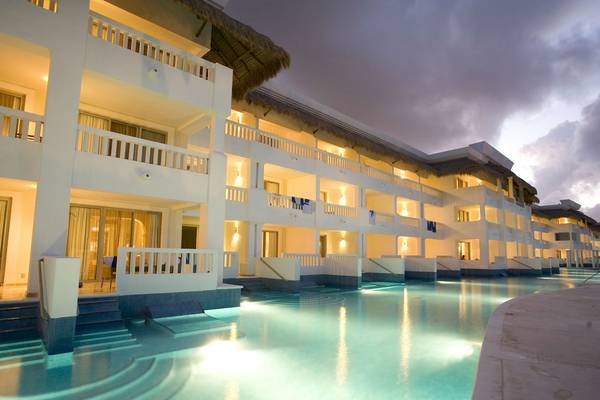 Außenansicht des Grand Riviera Princess Hotels bei Nacht mit beleuchteten Balkonen und einem großen Swimmingpool
