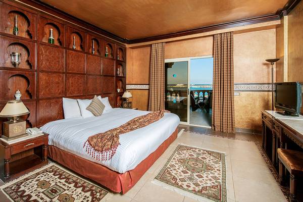 Innenansicht eines Schlafzimmers im Sentido Mamlouk Palace Hotel mit großem Bett, Nachttischen und Meerblick.