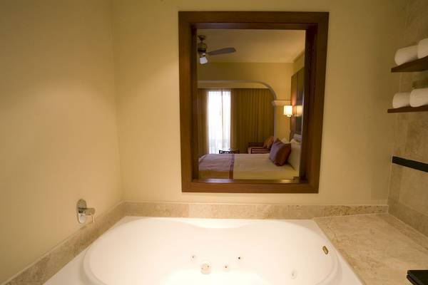 Badezimmer im Grand Riviera Princess Hotel mit Jacuzzi und Blick auf das Bett