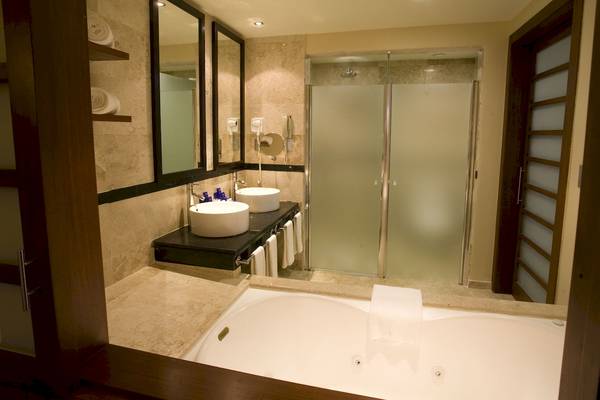 Badezimmer im Grand Riviera Princess Hotel mit Badewanne, zwei Waschbecken und Glasdusche.
