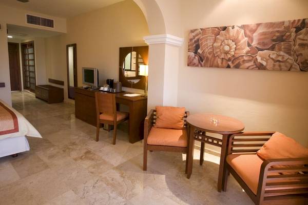 Innenansicht einer Hotelsuite im Grand Riviera Princess mit Bett, Schreibtisch und Esstisch.