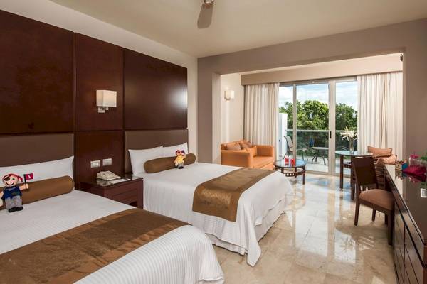 Hotelzimmer der Grand Riviera Princess mit zwei Betten, Deckenventilator und großer Terrassentür.