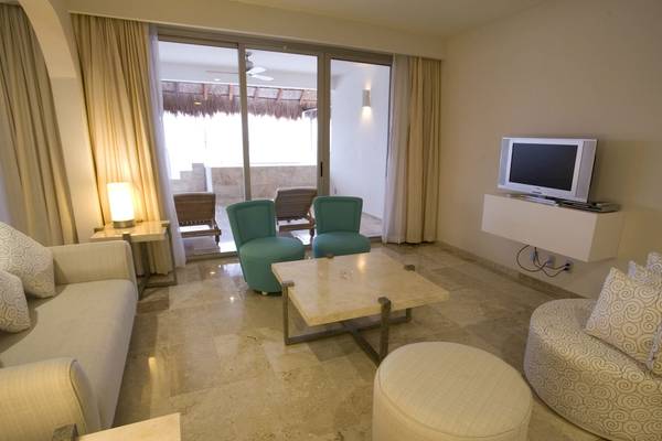 Wohnbereich im Grand Riviera Princess Hotel mit großem Fernseher und gemütlichen Möbeln.