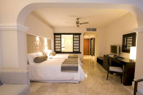 Ein modernes Hotelschlafzimmer mit zwei Betten, Schreibtisch, Fernseher und Deckenventilator.