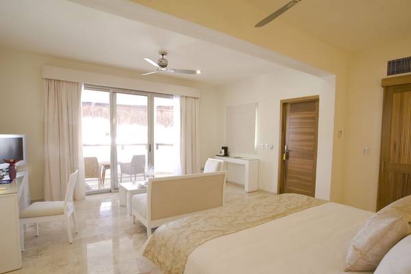Schlafzimmer im Grand Riviera Princess Hotel mit Bett, Schlafzimmermöbeln und Balkonzugang.