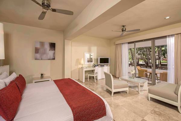 Suite-Schlafzimmer im Grand Riviera Princess Hotel mit Bett, Schreibtisch und Terrasse.