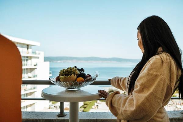 Frau auf Balkon mit Meerblick im Festa Panorama Hotel, Obstschale auf Tisch