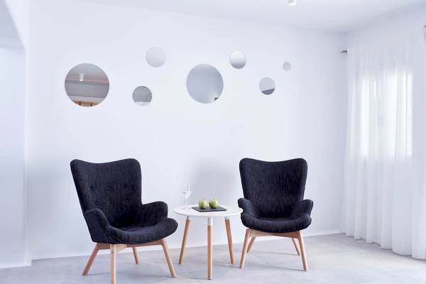 Lobby Sitzecke im Absolute Mykonos Suites & More Hotel mit weißen Wänden und runden Spiegeln.