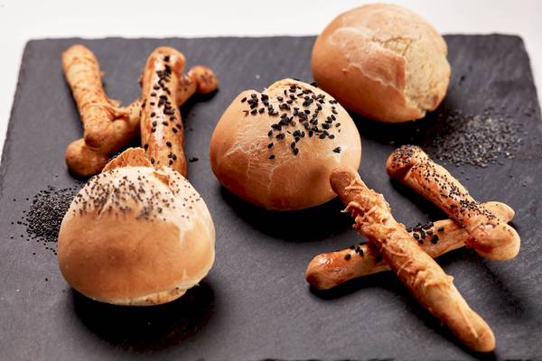 Mehrere gebackene Semmelknödel und Brötchen auf einem schwarzen Teller.