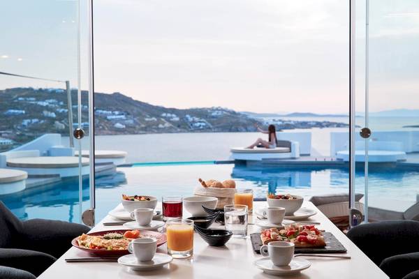 Frühstückstisch am Pool mit Blick auf das Meer im Absolute Mykonos Suites & More Hotel.