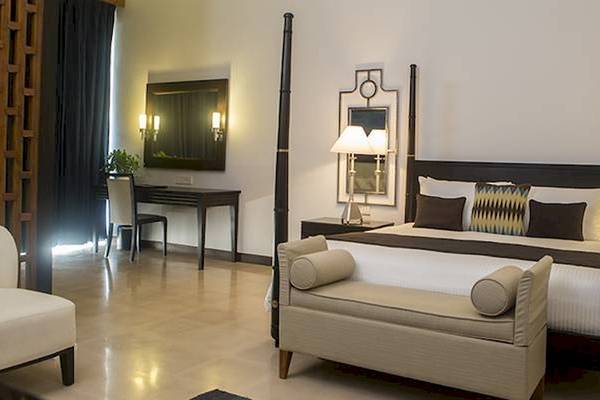 Schlafzimmer im Blue Water Hotel und Spa mit vierposterbett, kissen, nachttischen und lampen.