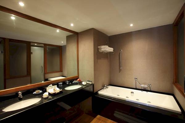 Ein Badezimmer im Blue Water Hotel und Spa mit zwei Waschbecken, einer Badewanne und einem großen Spiegel.