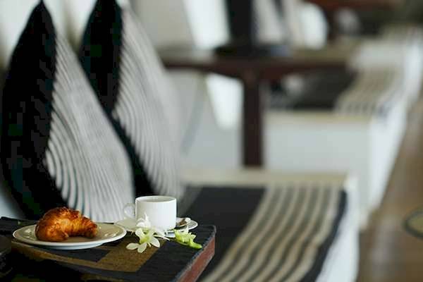 Sitzbereich im Blauen Wasser Hotel und Spa mit Kissen, Croissant, Tasse Kaffee und Blumen