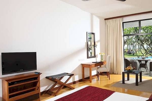 Hotelzimmer mit modernem Interieur, Fernseher, Schreibtisch und Blick auf einen Swimmingpool.