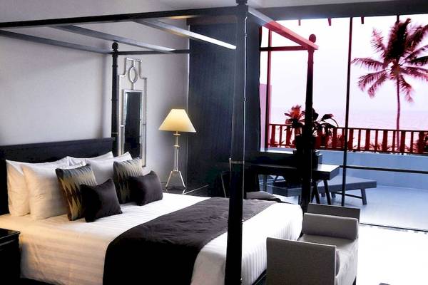 Schlafzimmer im Blue Water Hotel und Spa mit vier Pfostenbett, Fenstern und Blick auf die Palmen und das Meer.