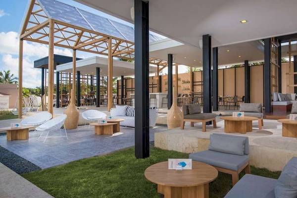 Terrasse des Catalonia Royal Bavaro Hotels mit Holztischen und Stühlen.