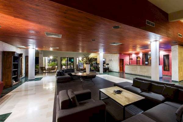 Innenbereich des Catalonia Royal Bavaro Hotels mit Sofas, Tischen und Holzdecke.