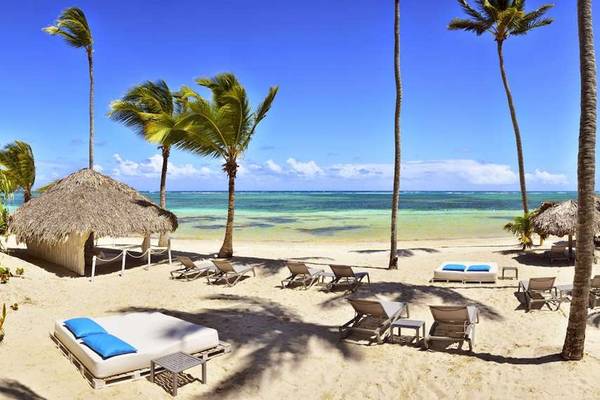 Strand des Catalonia Royal Bavaro Hotels mit weißen Liegen, Palmen und blauem Himmel